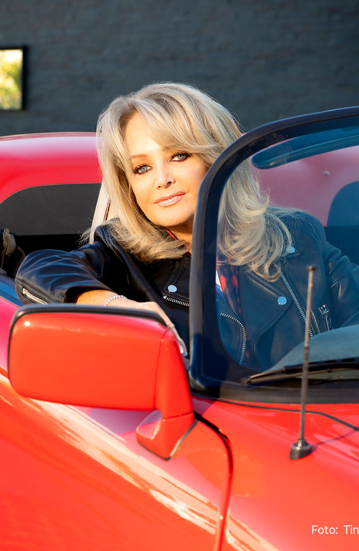 Bonnie Tyler sitzend in einem roten Cabrio