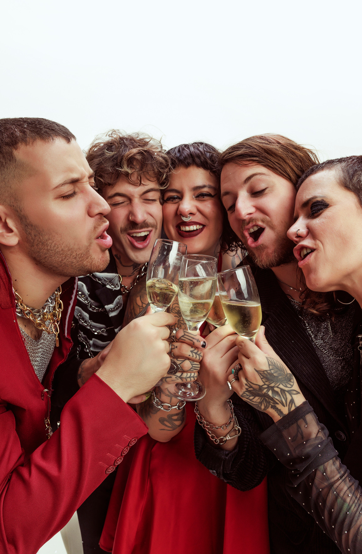 Eine Gruppe ausgelassener Freunde prostet mit Weingläsern an, eng umschlungen und lachend.